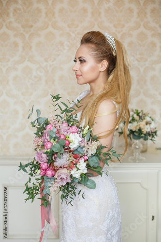 Pretty young Bride. Blonde-haired woman with wedding hair-style with a long tail. Boudoir morning of the bride. Looking to the camera or on her wedding bouquet