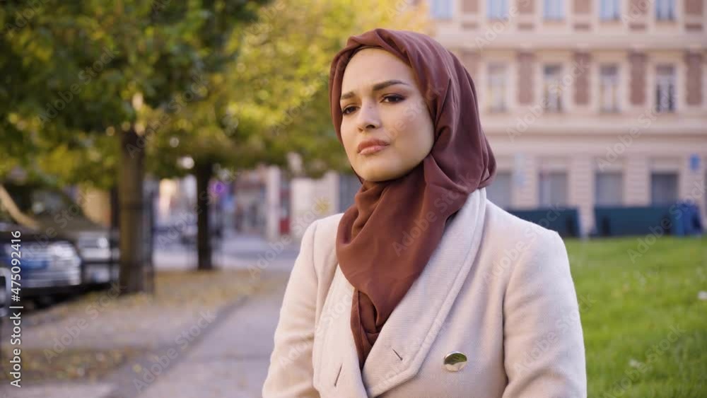 A young beautiful Muslim woman is sad and cries in a street in an urban area - closeup A young beautiful Muslim woman is sad and cries in a street in an urban area - closeup