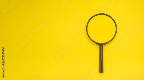 Overhead view of a magnifying glass isolated on a yellow background