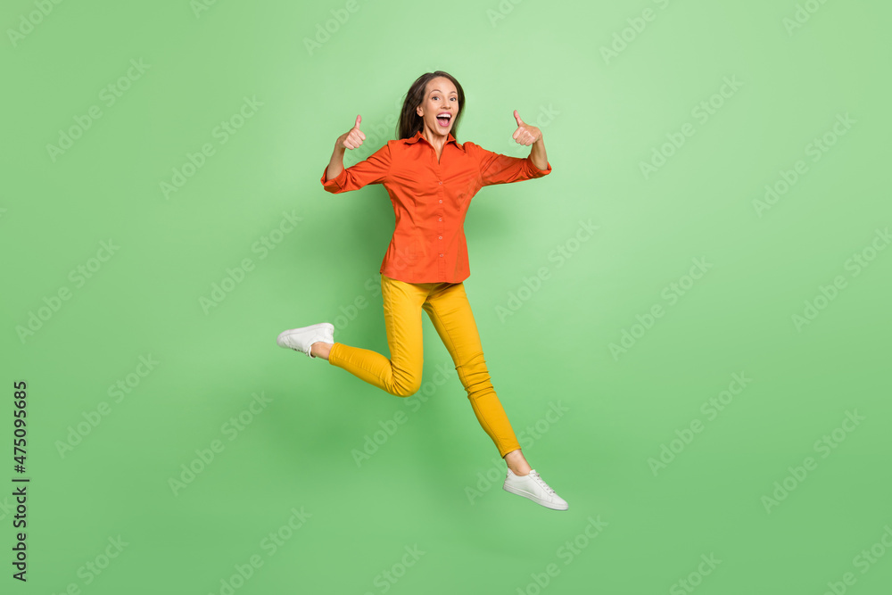 Full size photo of mature woman have fun jump show thumbs-up perfect great isolated over green color background