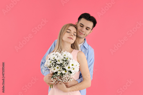 Cute couple with bouquet on pink background