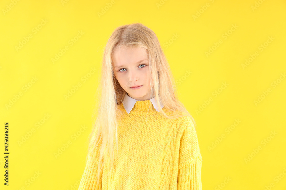 Resentful little girl in sweater on yellow background Resentful little girl in sweater on yellow background