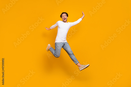 Full body photo of scared brunet young guy run wear shirt jeans sneakers isolated on yellow background © deagreez