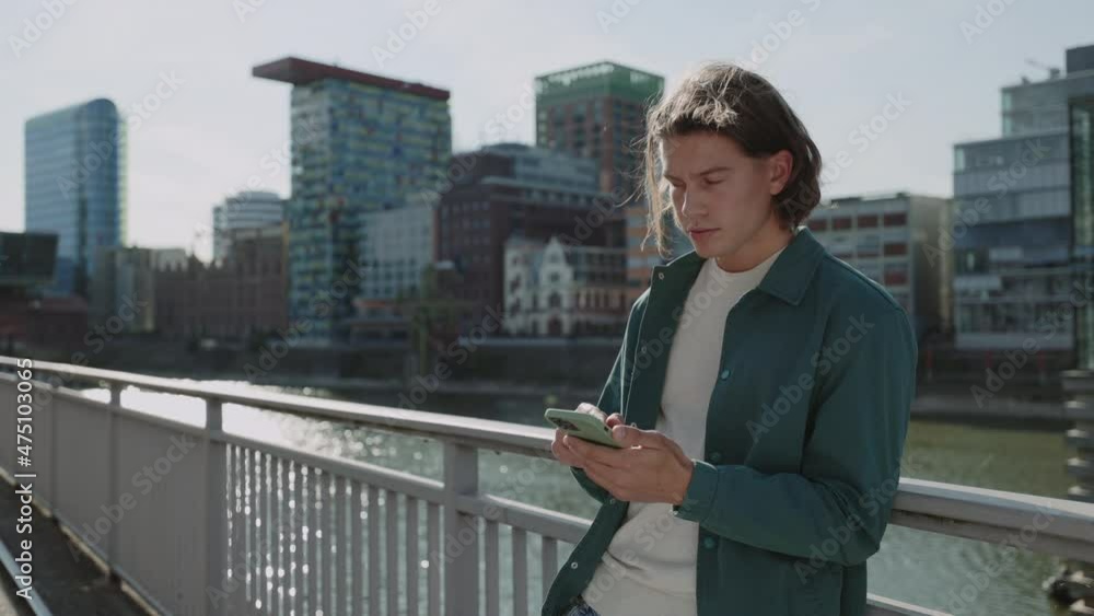 Young guy using modern smartphone standing on street Young guy using modern smartphone standing on street