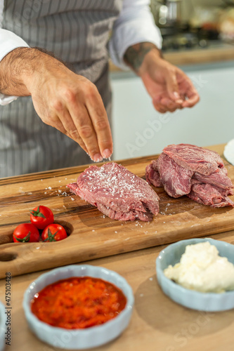 A close-up of a chef adding spices into a piece of meat
