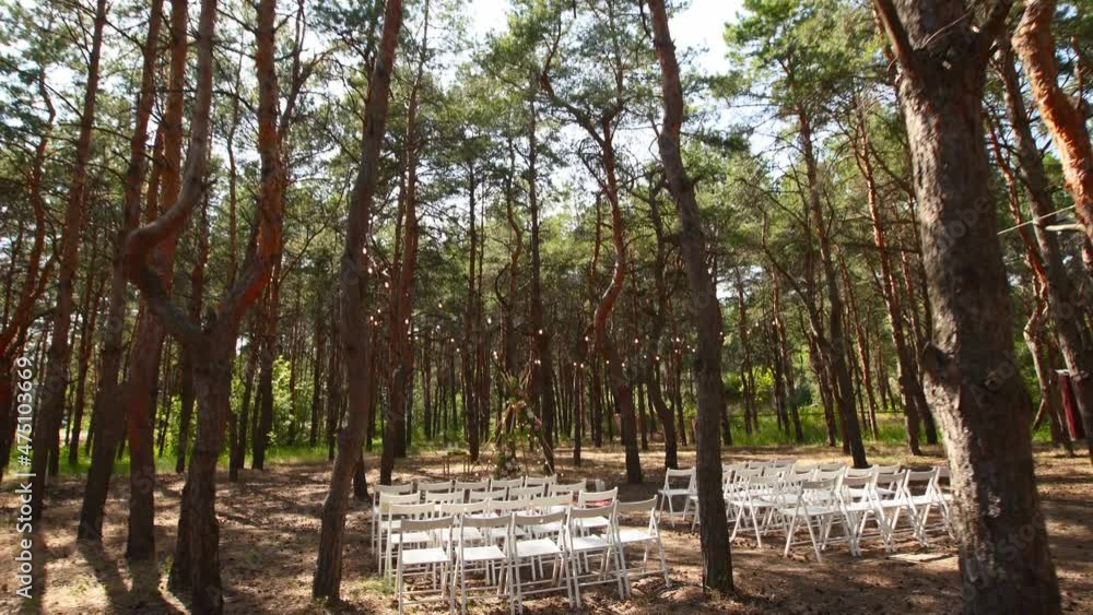 Beautiful bohemian tipi arch decoration on outdoor wedding ceremony venue in pine forest with cones. Chairs, floristic flower compositions of roses, carpet, string fairy lights. Summer rural wedding. Beautiful bohemian tipi arch decoration on outdoor wedding ceremony venue in pine forest with cones. Chairs, floristic flower compositions of roses, carpet, string fairy lights. Summer rural wedding.