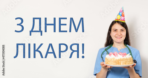 A woman holds a birthday cake, a banner with text on the Ukrainian, translated from Ukrainian: Happy Doctor's Day photo