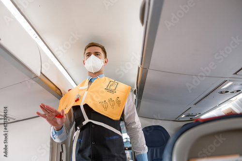 Flight attendant demonstrating how to use life vest in aircraft