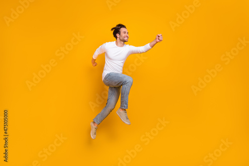 Full length photo of cute brunet millennial guy run wear shirt jeans shoes isolated on yellow background