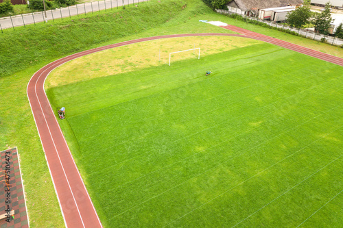 Aerial view of sports stadium with red running tracks and green grass football field