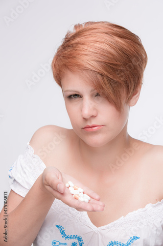 red haired woman with some medical pills looking skeptical