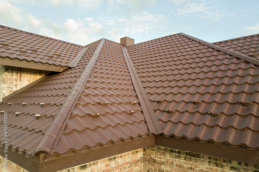 Detail of house roof structure covered with brown metal tile sheets
