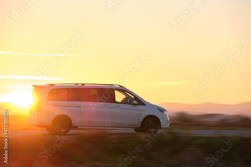 Passenger van driving fast on intercity road at sunset. Highway traffic in evening © bilanol