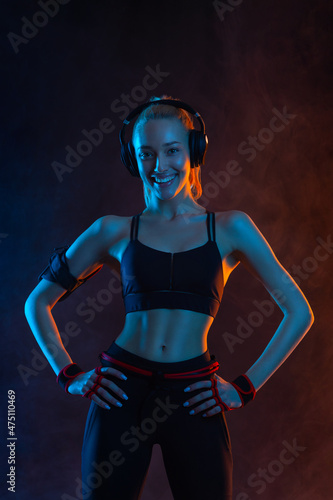 Strong athletic fit woman on black background wearing in the sportswear. Fitness and sport motivation.