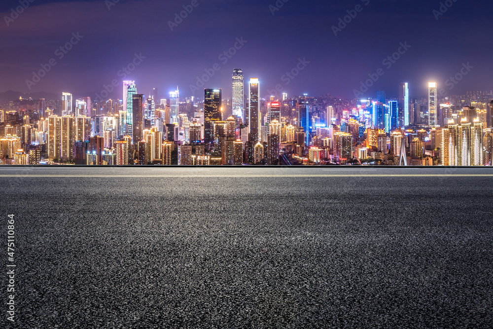 Panoramic skyline and modern commercial buildings with empty road. Asphalt road and cityscape at night.