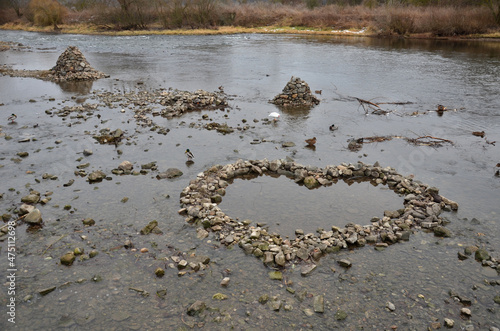 a low-flow riverbed attracts people to build mounds, hills and dams, which are broken again by waves during a flood. artificial hills and dry walls make the landscape special. heart made of stones photo