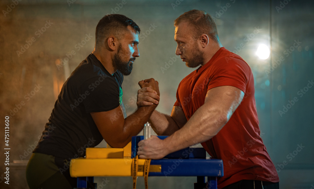 The Armwrestling. Two strong athletes in the gym compete in arm wrestling. Bodybuilders