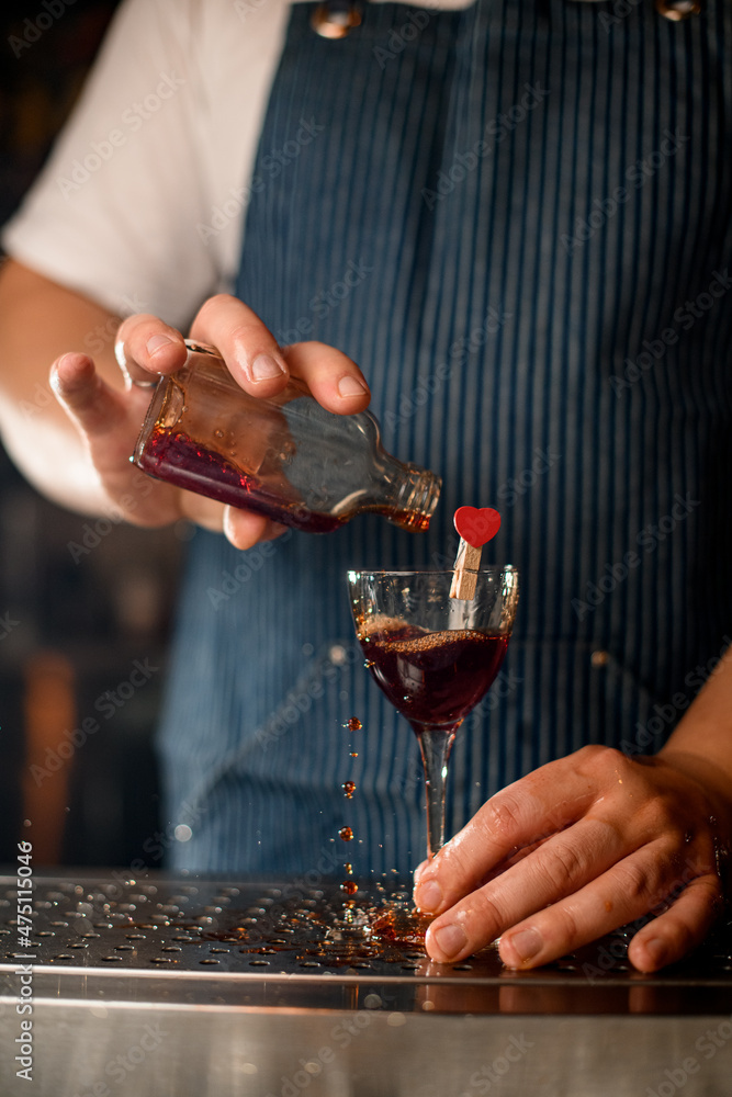 male hand holds wineglass decorated with heart and pours drink into it male hand holds wineglass decorated with heart and pours drink into it