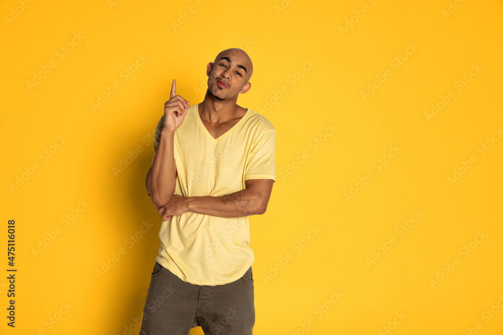 Emotional dark skinned man in t-shirt posing isolated on yellow color studio background. Concept of human emotions Emotional dark skinned man in t-shirt posing isolated on yellow color studio background. Concept of human emotions