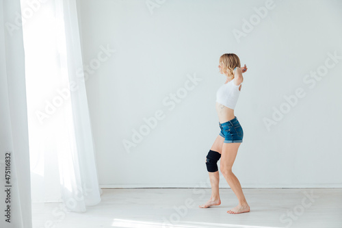 beautiful slender woman dancing to music in a white hall