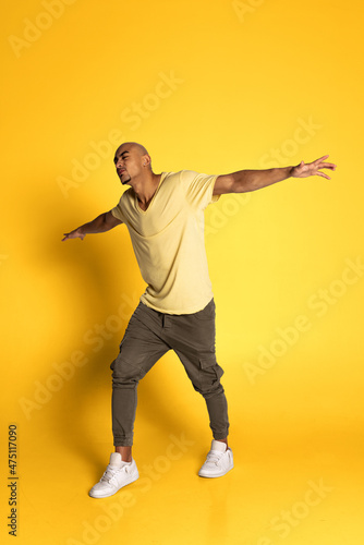 Portrait of African young man in casual clothes isolated on yellow color studio background. Concept of human emotions