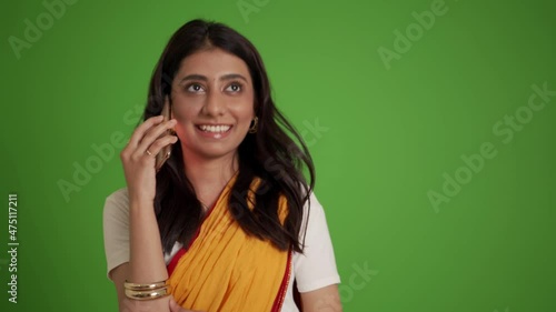Smiling traditional Indian woman talking by phone in the green studio photo