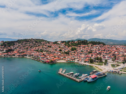 Drone view of the resort town of Ohrid. Drone shot overlooking Lake Ohrid and a small town against the backdrop of green mountains. A pier with boats in the center of Ohrid, a view from above.