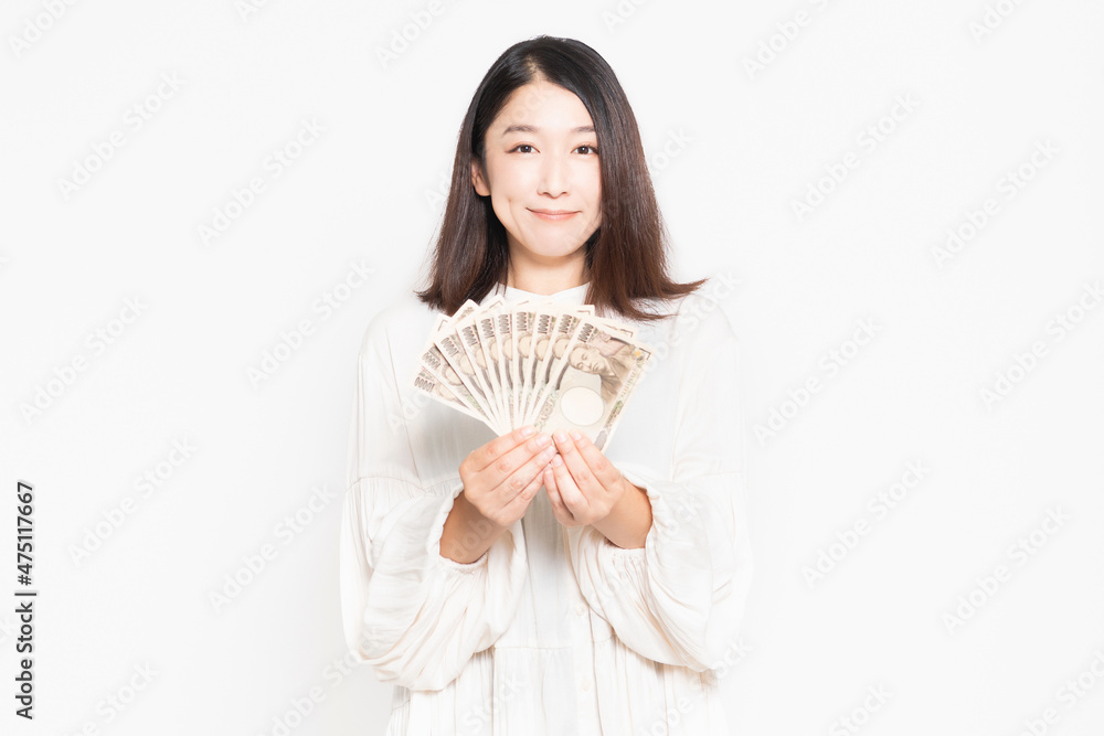 白い背景の前に立って、お金を見せる主婦