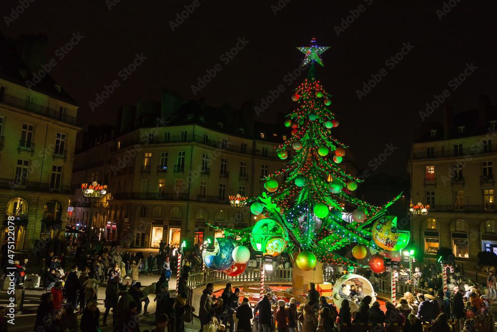 Fototapeta premium Marché et Festivités de Noël sur la place d'une ville en hiver, avec sapin géant qui sert de manège. Nantes, France