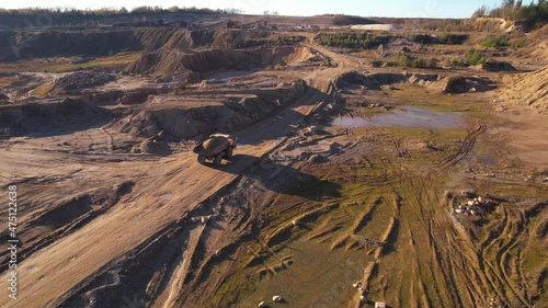 Mining truck transported sand from the open pit. Dump truck working in quarry. Arial view of the opencast mine. Limestone and gravel is excavated from ground. Mining industry. photo