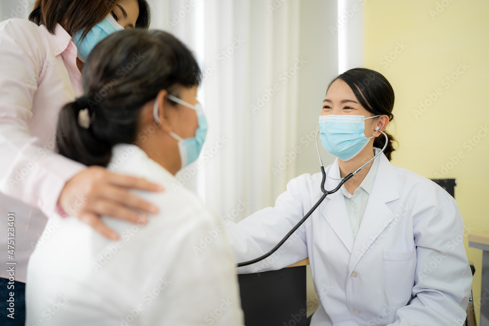 Asian female doctor talking to an elderly woman To maintain health with a smile, the concept is to take care of health, elderly patients, teenage doctors. check heartbeat wearing a mask Asian female doctor talking to an elderly woman To maintain health with a smile, the concept is to take care of health, elderly patients, teenage doctors. check heartbeat wearing a mask