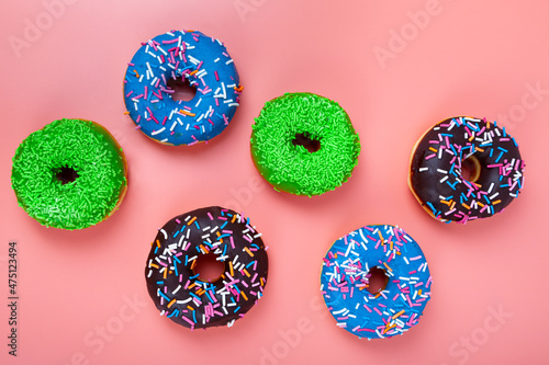Delicious multicolored donuts on a pink background.