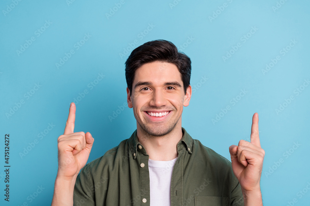 Portrait of positive guy promoter point index finger empty space indicate promo ads isolated over blue color background Portrait of positive guy promoter point index finger empty space indicate promo ads isolated over blue color background