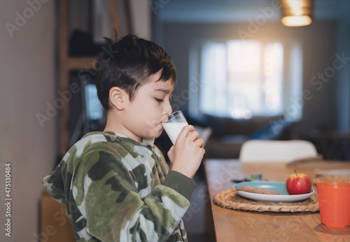 Portrait healthy school boy drinking glass of milk for breakfast, Happy child sitting in dining room drinking warm milk before go to school. Healhty food liftstyle concept photo