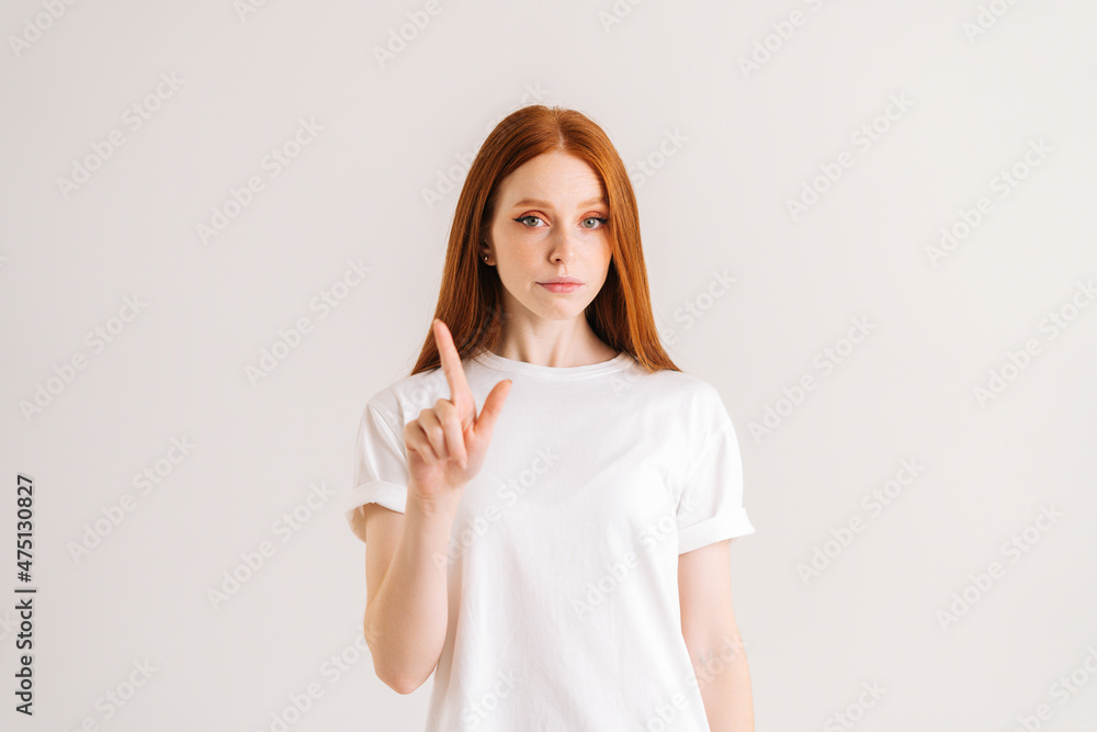 Portrait of confident young woman shaking finger in prohibition gesture, show no and disagreement, standing on white isolated background in studio. Serious redhead female shaking head in disagreement Portrait of confident young woman shaking finger in prohibition gesture, show no and disagreement, standing on white isolated background in studio. Serious redhead female shaking head in disagreement
