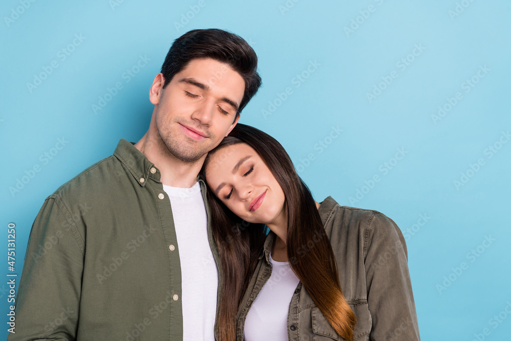 Photo of pretty cute young guy woman dressed khaki shirts smiling hugging closed eyes empty space isolated blue color background Photo of pretty cute young guy woman dressed khaki shirts smiling hugging closed eyes empty space isolated blue color background