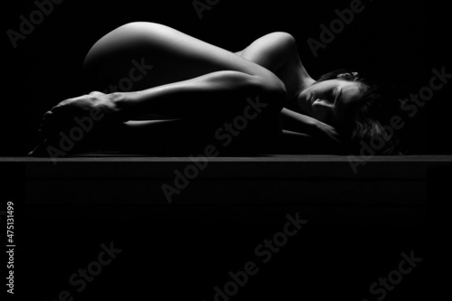 nude woman sleeping and resting sensual naked isolated on black studio background