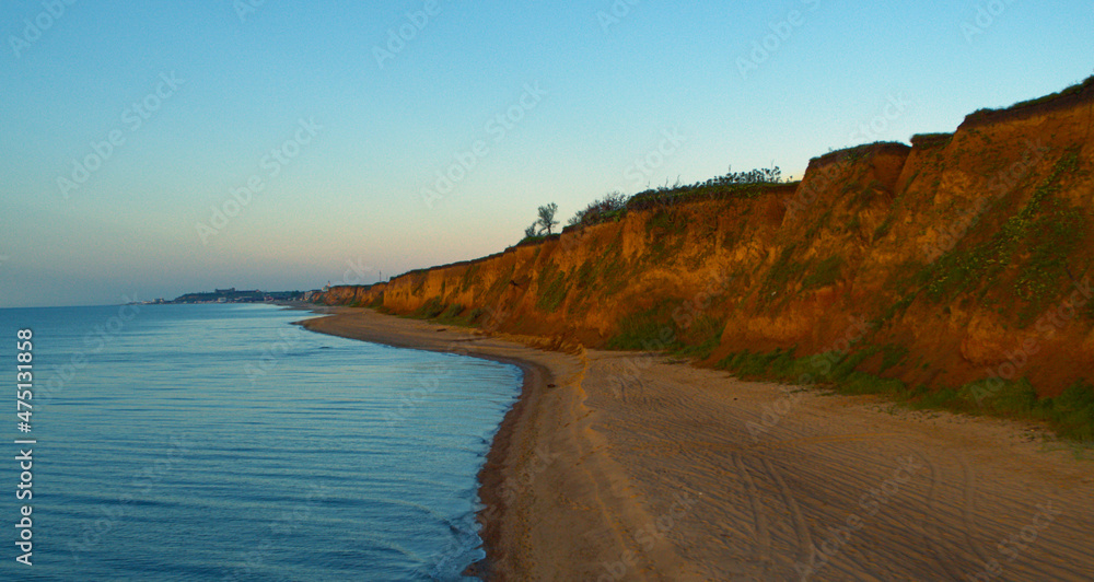 Aerial rocky beach view with charming cloudless sky. Waves splashing on beach.