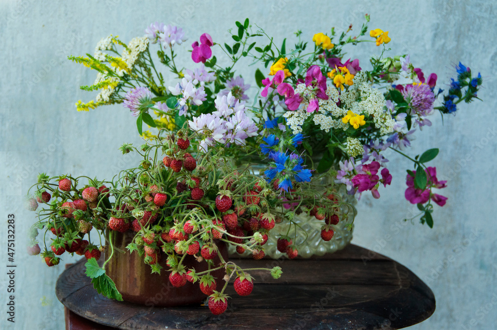 wildflowers bouquet and wild strawberry at stucco wall, rustic still life wildflowers bouquet and wild strawberry at stucco wall, rustic still life