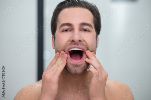 Man with open mouth examining his teeth