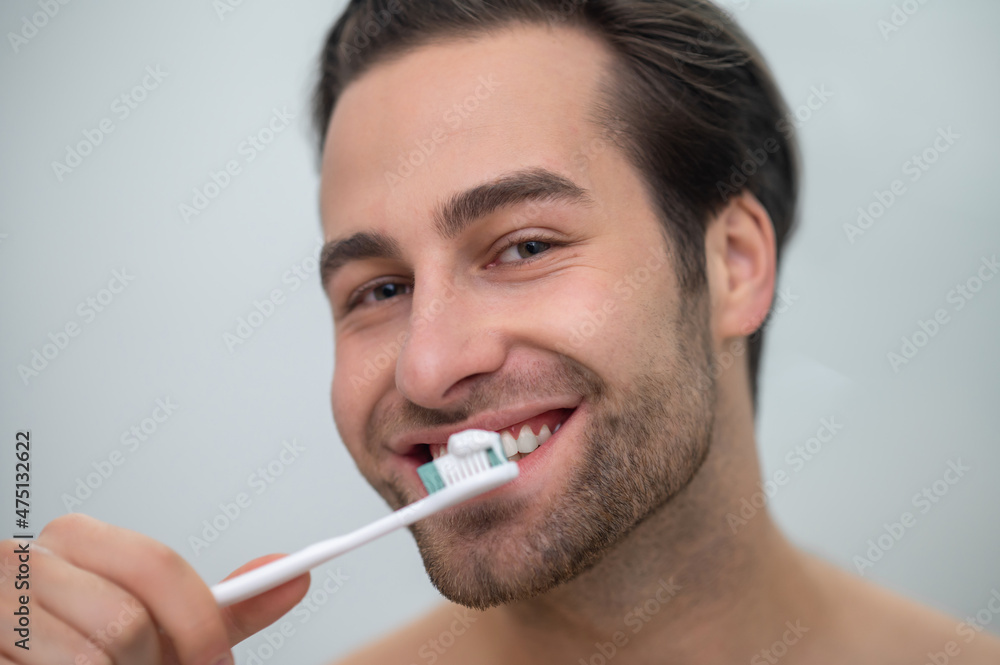 Smiling contented man brushing his teeth Smiling contented man brushing his teeth
