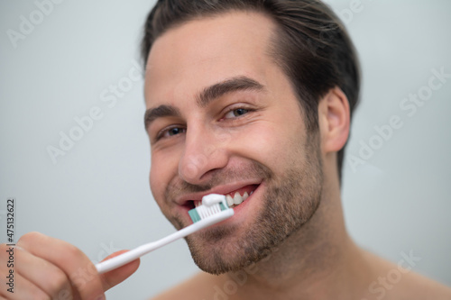 Smiling contented man brushing his teeth