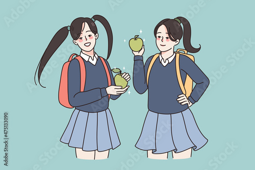 Smiling girls pupils in school uniform and backpacks having lunch eating apple. Happy female students enjoy break in college or university. Education and learning concept. Flat vector illustration. 