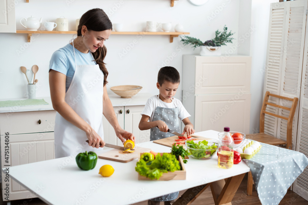 mother with her son are cooking together healthy vegetable salad