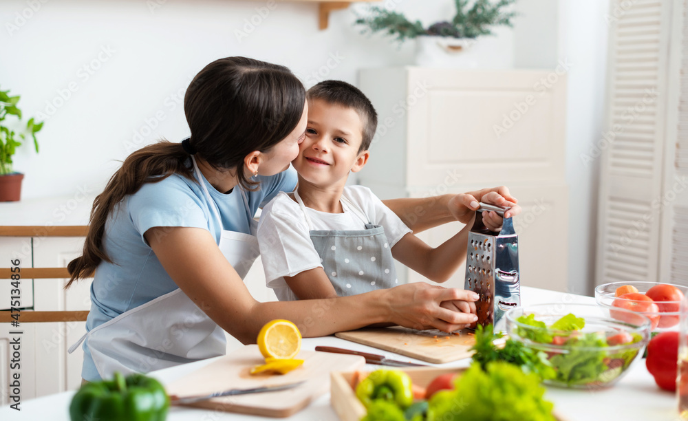 Mother and son are grating carrot, cooking together at home Mother and son are grating carrot, cooking together at home