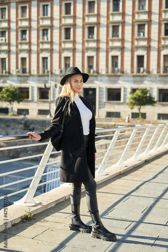 Young positive woman in black jacket and hat on bridge Young positive woman in black jacket and hat on bridge
