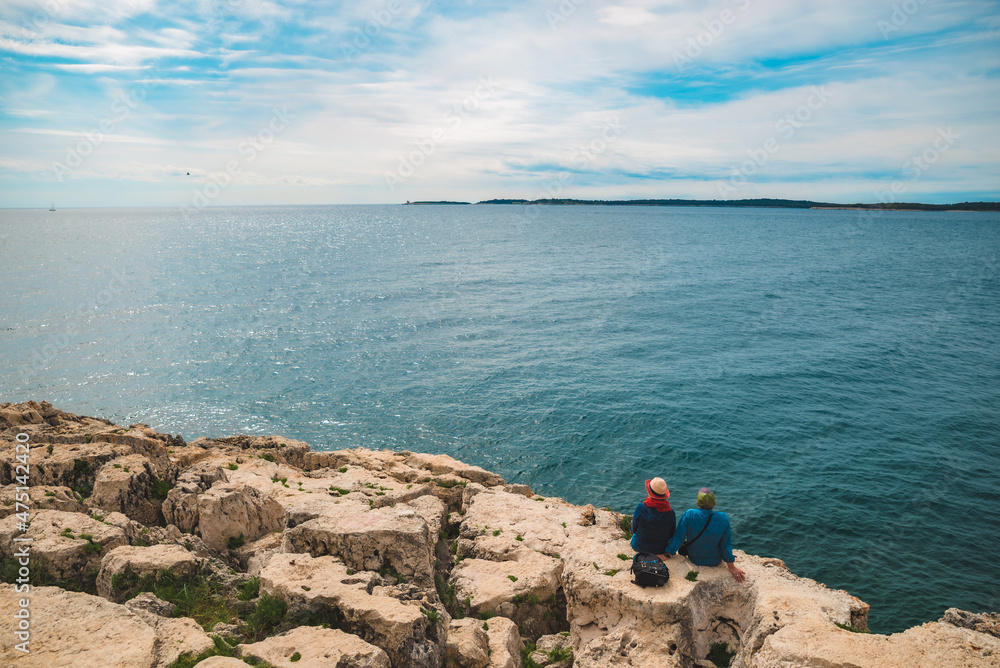 Pula, Croatia - May 21, 2019: senior couple sitting enjoying view of sea bay