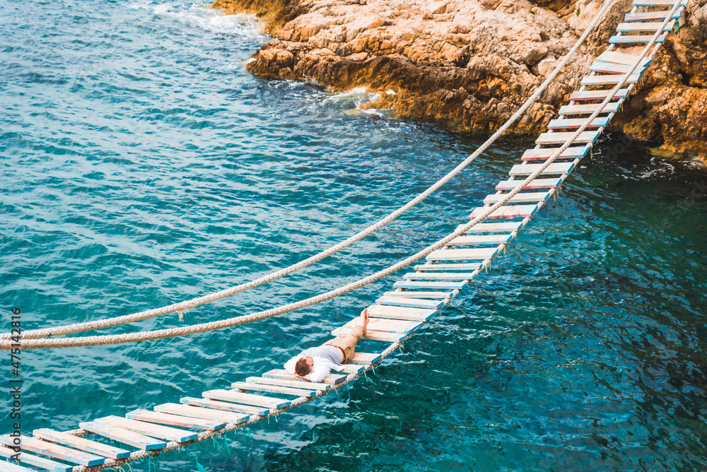 man laying at suspension bridge enjoying sea view and nature calmness