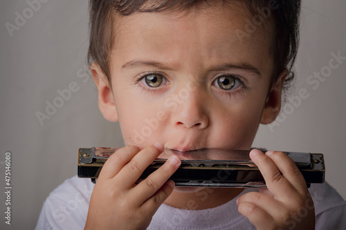 portrait of little boy making music with a harmonica