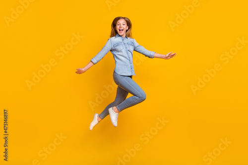 Full length photo of impressed small girl run wear bag jeans shirt shoes isolated on yellow background